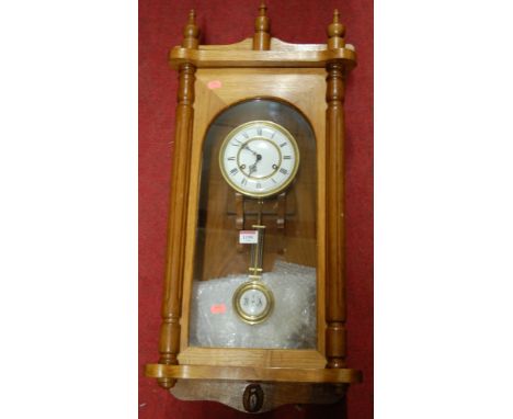 An oak drop trunk wall clock having a white enamel dial, twin winding holes and pendulum