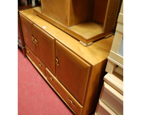 An Ercol blond elm sideboard having three cupboard doors over twin lower drawers
