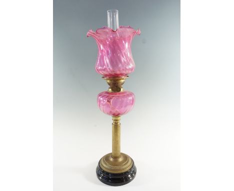 A Victorian columnar brass and cranberry glass oil lamp, having a duplex coronet burner, 61 cm to top of shade