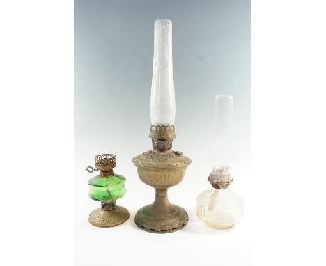 An early 20th Century embossed brass oil lamp together with two others having glass fonts, largest 31 cm excluding chimney