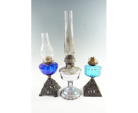 Two early 20th Century cast iron and blue glass oil lamps, both having single wick prong burners, together with a chrome plat