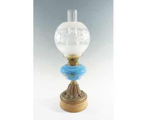 An early 20th Century brass and blue glass oil lamp, having a floral decorated glass font on an embossed brass pedestal with 