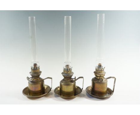 A pair of early 20th Century brass finger lamps having concentric wicks, together with a similar lamp, 37 cm