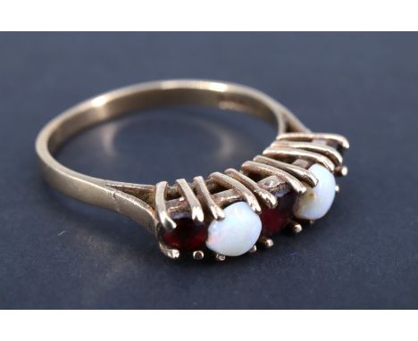 An opal and garnet finger ring, having three graduated garnet brilliants separated by two 4 mm opal cabochons, claw set in a 