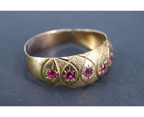 A vintage ruby and yellow metal finger ring, the convex adorsed tapering band gypsy-set with a line of seven brilliant rubies