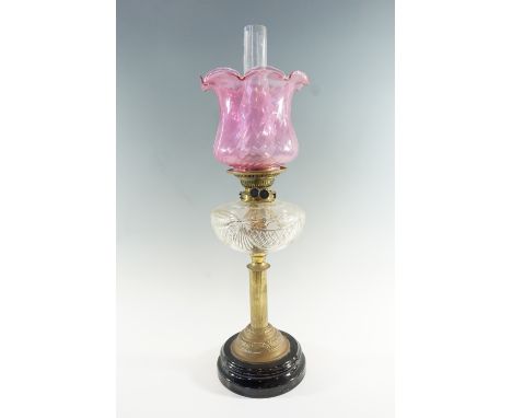 A Victorian columnar brass and cut glass oil lamp, having a duplex coronet burner and crinoline edged cranberry shade, 63 cm 