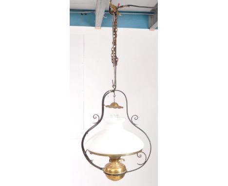 An early 20th century oil lamp hanging ceiling light. The light having lyre shaped metal frame, with scrolled details. Featur