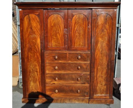 A 19th century Victorian mahogany compactum triple wardrobe. The wardrobe of breakfront form, featuring a central chest of dr