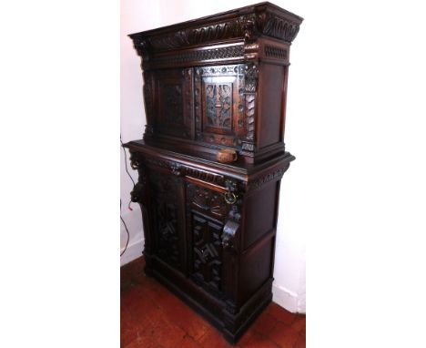 A 19thC carved oak cupboard, with gadrooned frieze over fish scales and arabesque doors, lion mask drawer to base over two ar