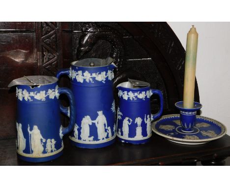 Three Wedgwood blue Jasperware graduated jugs, 17cm, 14cm and 12cm, and a Wedgwood candlestick. (4) 