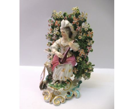 18th Century Derby figure of a seated shepherdess before a boccage playing a musical instrument, 19.5cm high