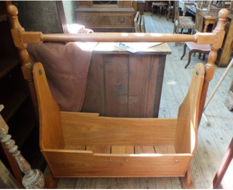 A solid light Oak swing crib on stand