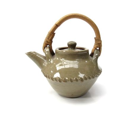 CLEMENT KOFI ATHEY (b.1922, Ghana.) A stoneware teapot in greenish grey glaze, cane handle. The base incised CKA and written 