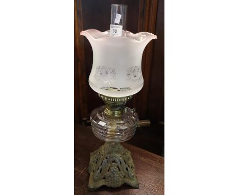 Early 20th Century double burner oil lamp having frosted glass shade, clear glass reservoir and standing on a pierced cast me