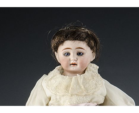 A small bisque shoulder-head doll, with fixed blue eyes, head turned slightly to the right, brown hair wig, gusseted kid body