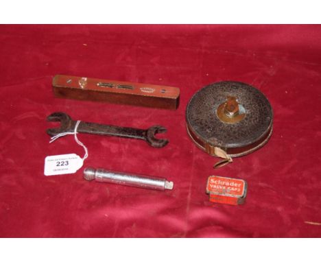 A vintage Schroder tyre gauge and valve cap tin; a small Ford spanner; an old leather cased tape measure, and a small brass f