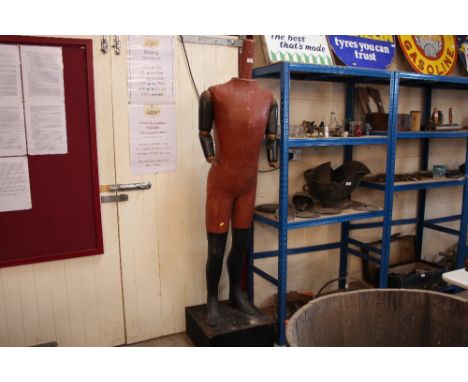 An old painted wooden and papier maché mannequin with jointed arms, raised on a plinth, 190cm high 