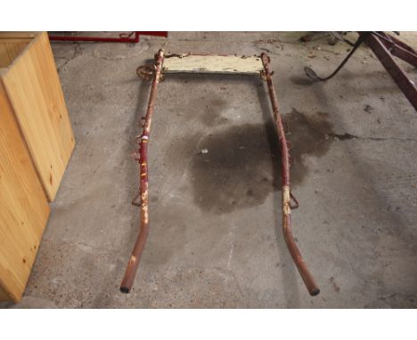 A pair of vintage metal cart shafts with a metal step