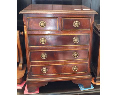 An oak apprentice chest of two short and three long drawers with brass ring handles and bracket feet