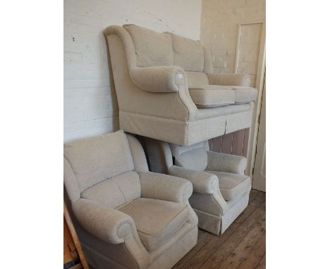 A beige upholstered three piece suite comprising a two seat sofa and two armchairs