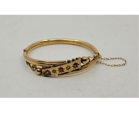 A Victorian 9ct. gold, ruby and diamond set hinged bangle,&nbsp;Birmingham 1900, the front gypsy set three mixed round cut ru