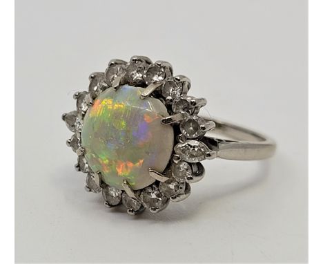 An 18ct. white gold, platinum, opal and diamond cluster ring, set circular cabochon opal to centre bordered by marquise cut d