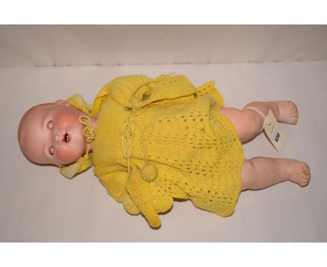 A German porcelain head doll by Armand Marseille, No. 351/4K, with yellow knitted dress and cardigan.