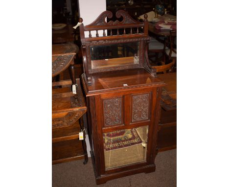 A late Victorian carved and stained wood music cabinet, the back panel with bevelled mirror and shelf over, above a panelled 