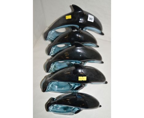 Five Poole pottery graduated dolphins.