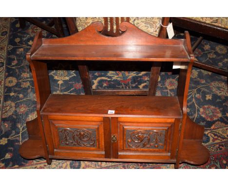 A Victorian walnut wall mounted shelf unit, with two ornate carved panelled doors flanked by shaped shelves.