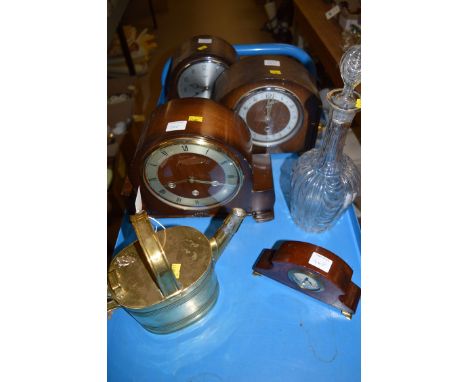 A brass watering can; a glass decanter and stopper; and four mantel clocks.