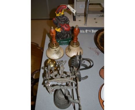 A metal punch door stop; two brass hand bells; a hanging bell on bracket; etc.