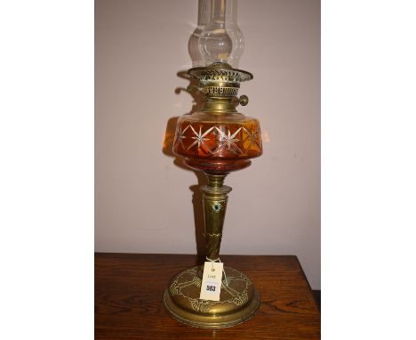 An Arts & Crafts oil lamp with cut glass reservoir and brass stand, with coloured cabochon mounts.