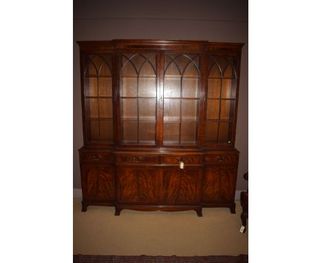 A reproduction mahogany breakfront bookcase, with flared cornice above four glazed panelled doors enclosing shelves, fitted f