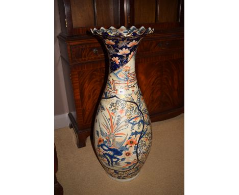 A large Asian ceramic vase with flared wavy rim, decorated in Imari colours, depicting exotic birds, foliage, shrubbery and g