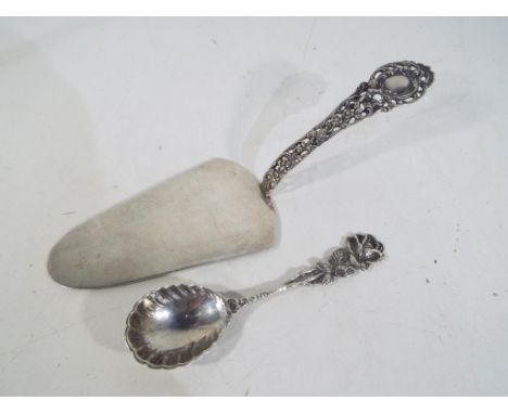 A silver cake slice with pierced decorated handle stamped 800 and a silver tea caddy spoon with a floral decorated handle sta