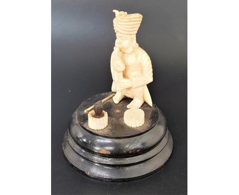 INDIAN IVORY CARVED GROUPdepicting a snake charmer crouching down, with a stick beside him and a black cobra rising from a ba