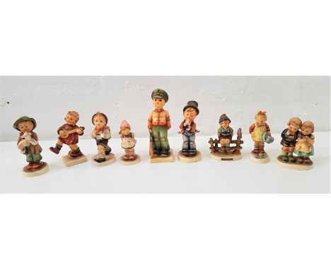 NINE GOEBEL HUMMEL FIGURESincluding a boy sitting on a fence, a girl with watering can, a boy holding a lamb, and a boy dress