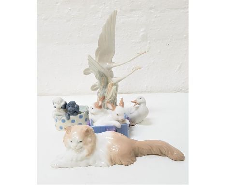 FIVE NAO FIGURINEScomprising a pair of herons in flight, 27cm high; a relaxing cat, 25.5cm long; two poodles in a basket, 8cm