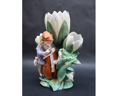 A continental porcelain triple lily vase moulded with a bearded sprite playing a cello with the score held by a toad, blue ma