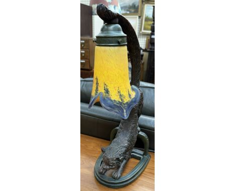 A table lamp in the form of a cat with its tail raised holding aloft a glass lamp shade