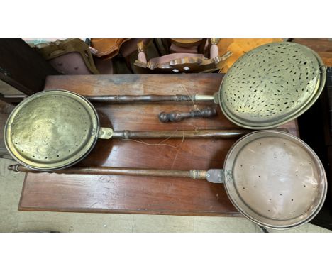 A brass bedwarming pan together with another brass bedwarming pan and a copper bedwarming pan