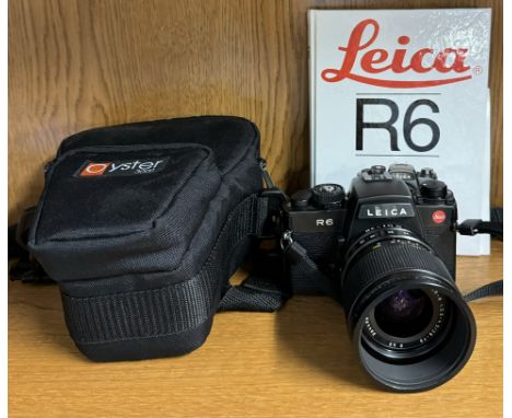 A Leica R6 35mm camera with a Leica Vario-Elmar-R 1:3.5-4.5/28-70 lens and book on the camera