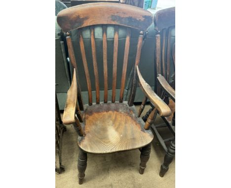 A 19th century kitchen elbow chair with a slat back and solid seat on ring turned legs