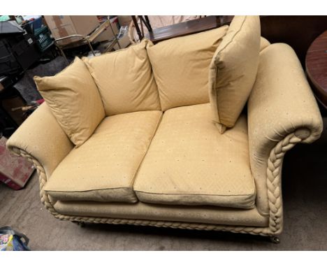 An upholstered two seater settee with four separate cushions and rope twist front on turned legs