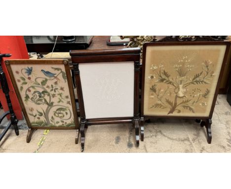 A Victorian rosewood firescreen with a sliding screen on reeded legs and casters together with two woolwork decorated fire sc