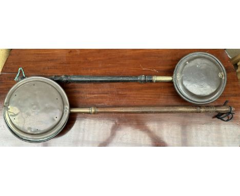 A copper bedwarming pan together with another bedwarming pan