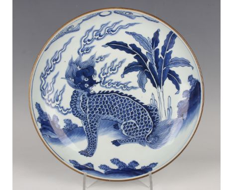 A Chinese blue and white porcelain circular dish, late Qing dynasty, painted with a seated kylin, vapours and banana plant, a