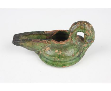 An Islamic green glazed pottery oil lamp, probably Isfahan, 12th century, the squat body with tapered spout and loop handle, 