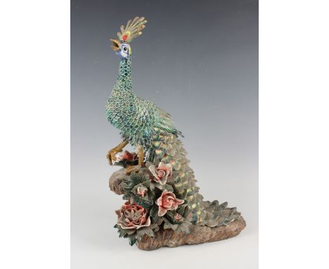 A Chinese pottery model of a peacock, 20th century, modelled on a flower encrusted rocky outcrop, with turquoise and blue gla